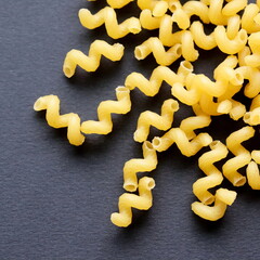 Pasta. Spiral macaroni. Raw uncooked macaroni isolated on black background, close up, top view.