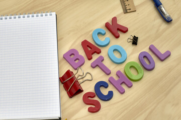 the phrase back to school is laid out in multicolored letters on the table a fountain pen a ruler stationery clips a notebook next to the concept of education school