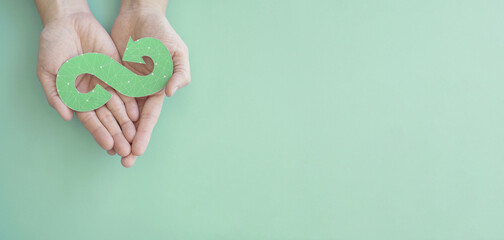 Hands holding green infinity arrow symbol, circular economy, sustainable and responsible business growth concept - 517298350