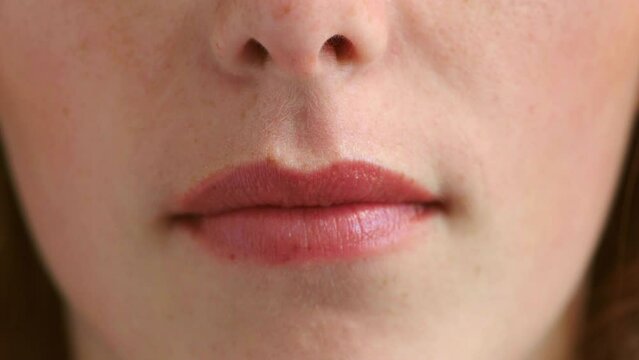 Closeup of womans perfect lips with natural pink lipstick or lipgloss. Headshot, face and macro detail of woman with permanent lip makeup or wearing fresh cosmetics on her mouth while standing alone
