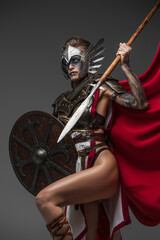 Portrait of antique strong woman with shield and spear dressed in armor and red cloak.