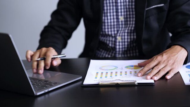 Businessman is deeply reviewing a financial report for a return on investment or investment risk analysis on a tablet and laptop computer notebook.