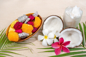 Tropical fruit bowl and coco drink on sand beach background.