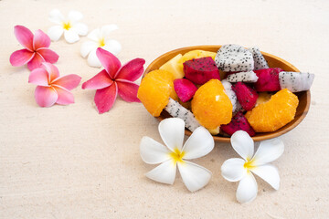 Obraz na płótnie Canvas Mixed tropical wooden fruit bowl on sand beach.