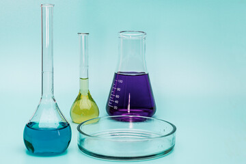 Three glass medical laboratory flasks with different multi-colored liquids and a glass bowl. The concept of medical and chemical experiments. Laboratory analysis of liquids. close-up. copyspace.