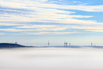 Wind turbines above the morning fog
