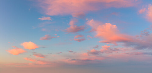 Naklejka na ściany i meble Pastel light pink clouds in the blue sky during dawn sunset, sky background