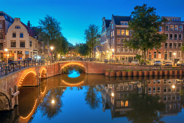 Obraz premium Amsterdam. Blue dusk before dawn. Typical old houses and bridges, illumination. Reflection in water. Amsterdam, Holland, Netherlands