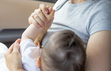 young mother breastfeeding baby boy on car seat. motherhood and lactation concept.cute adorable little boy eating breast milk.nursing infant in public.sunny .World Breastfeeding Week,august 1 august 7