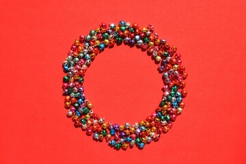 Little christmas colourful jingle bells round wreath on red background and copy space for text. Holiday festive happy new year concept. Greeting postcard, poster, banner. Mock up, flatlay, top view