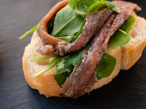 Cichetto or Venetian Appetizer or Tapas with Bread, Anchovies or Acciuga and Fresh Spinach Leaves