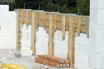 A reinforced concrete beam and pillars and a wooden formwork on the first floor of a house under construction, walls made of autoclaved aerated concrete, some reinforced brick lintels
