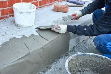 a worker uses a spatula to distribute the cement mixture along the ramp