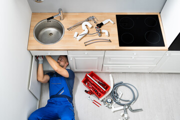 Plumber Fixing Faucet In Kitchen