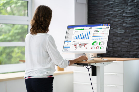 Woman Using Adjustable Height Standing Desk In Office