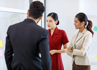 Asian young beautiful professional successful businesswoman standing smiling holding hand presenting showing graph chart report data paperwork documents on glass board to male and female colleagues