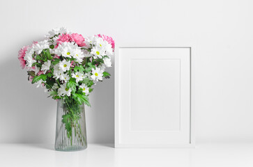 Portrait frame mockup in white minimalistic interior with fresh flowers bouquet