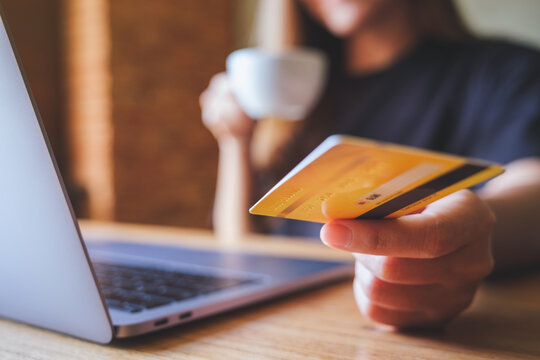 Closeup image of a business woman holding and showing a credit cards while using laptop computer for online payment