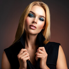 Photo of young stylish  woman in black clothes with  blue make-up. Portrait of sexy blonde woman with a beautiful face. Fashion model with long hair, studio shot.