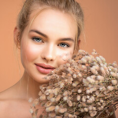Portrait of young beautiful woman with a healthy  skin of face.  Attractive girl with a bunch spring field flowers