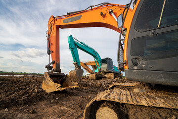 A backhoe or excavator works on a developer area  into a real estate construction site