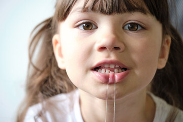 A girl with dental floss wants to pull out a loose tooth. Teeth in two rows. Shark tooth. The...