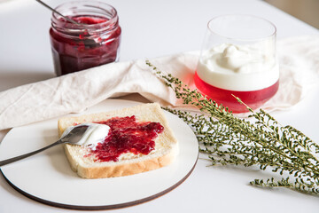 Break to eat. Pleasant and tasty moment of relaxation and tasting. Table with a glass of strawberry and yogurt gelatin and toast with red fruit jam.