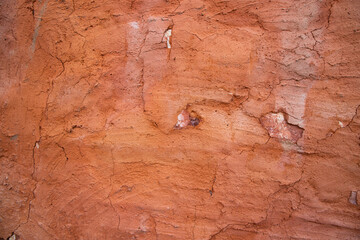 The texture of a red concrete wall with cracks and scratches can be used as a background