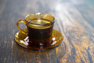 A cup of Indonesian black java coffee on wooden table with flare light background