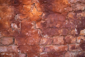 The texture of a red concrete wall with cracks and scratches can be used as a background