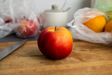 Red apple lies on a wooden cutting board in the kitchen