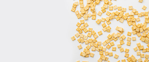 Crispy square shaped cracker scattered on white background. Top view, flat lay. Banner