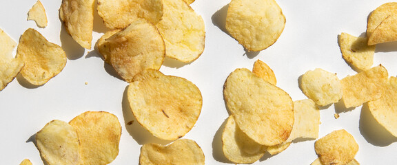 Chips are scattered on a white background. Top view, flat lay. Banner