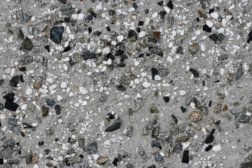 Concrete wall texture with pebbles. Decorative rough concrete surface with white, black and gray stones. Perfect for background and design. Closeup. High resolution.