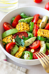 Salad with corn, avocado, tomatoes, peppers and parsley. Healthy eating. Vegetarian food.