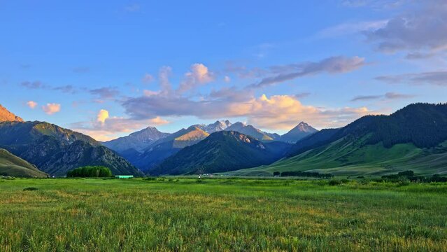Beautiful mountain and colorful cloud nature scenery in Xinjiang at sunset, China. Green grassland with mountains nature landscape.