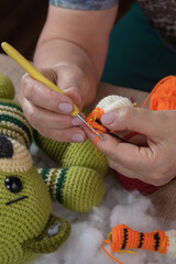 A woman has a crochet hook in her hands. She knits amigurumi toys.