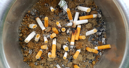Top view Many cigarette butts in ashtray or sand after people smoked. garbage, pollution or health concept