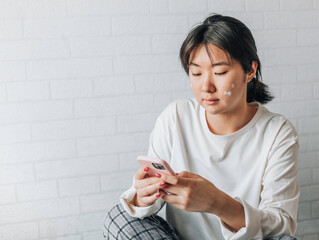 girl is texting on a smartphone while sitting on a bed at home. copy space. teenage girl with...