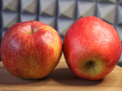 Two large red apples on a wooden surface. Ripe fruit