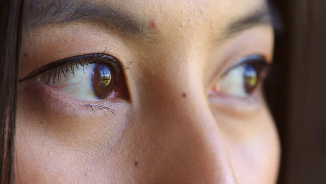Closeup of womans eyes showing sadness or stress while looking outside, scared with social anxiety. Headshot, face detail of woman watching, dreaming or thinking of past memory, longing to escape