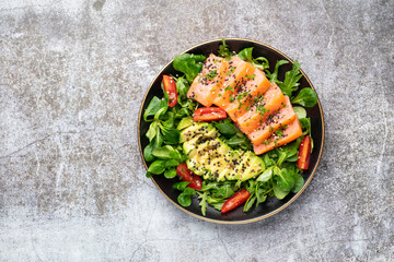Salmon fish fillet with fresh salad, avocado top view.