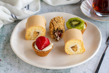 Delicious snacks. Roll cake, chocolate chip cake and fruit tart on a stone background. close up