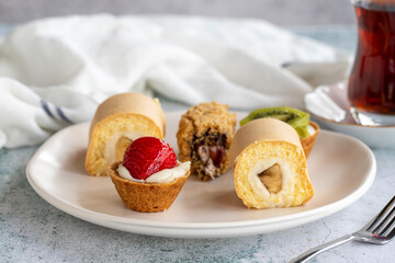 Delicious snacks. Roll cake, chocolate chip cake and fruit tart on a stone background. close up