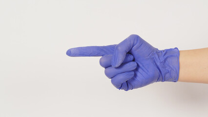 Hand is doing pointing finger (side view) hand sign on white background. Hand wear violet or purple latex glove.
