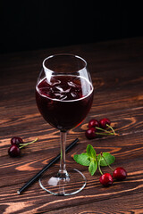 red cold summer alcoholic cocktail in a wine glass on wooden table.