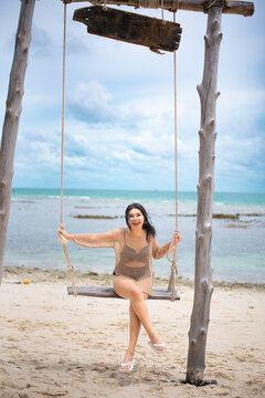 beautiful woman sitting on a swing on the beach on vacation