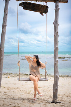 beautiful woman sitting on a swing on the beach on vacation