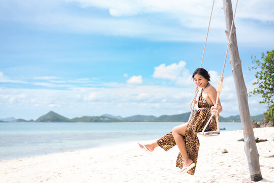 beautiful woman sitting on a swing on the beach on vacation