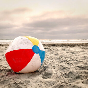 Beach ball laying in the sand at the beach, in vintage tone.